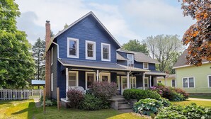 Une maison à deux étages avec un porche à l’avant, une cheminée en briques et une pelouse bien entretenue.