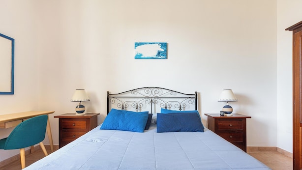 A bedroom with a bed, two bedside tables, a desk, a chair, and a wall-mounted picture. - Domus Maris Felloniche by BarbaHouse (Castrignano del Capo)