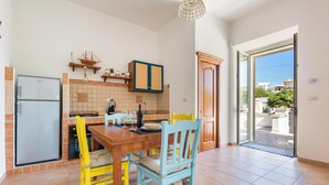 A kitchen with a dining table, chairs, a refrigerator, and a window. - Domus Maris Felloniche by BarbaHouse (Castrignano del Capo)