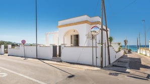 A white building with a small entrance, a no parking sign, and a clear view of the sea. - Domus Maris Felloniche by BarbaHouse (Castrignano del Capo)