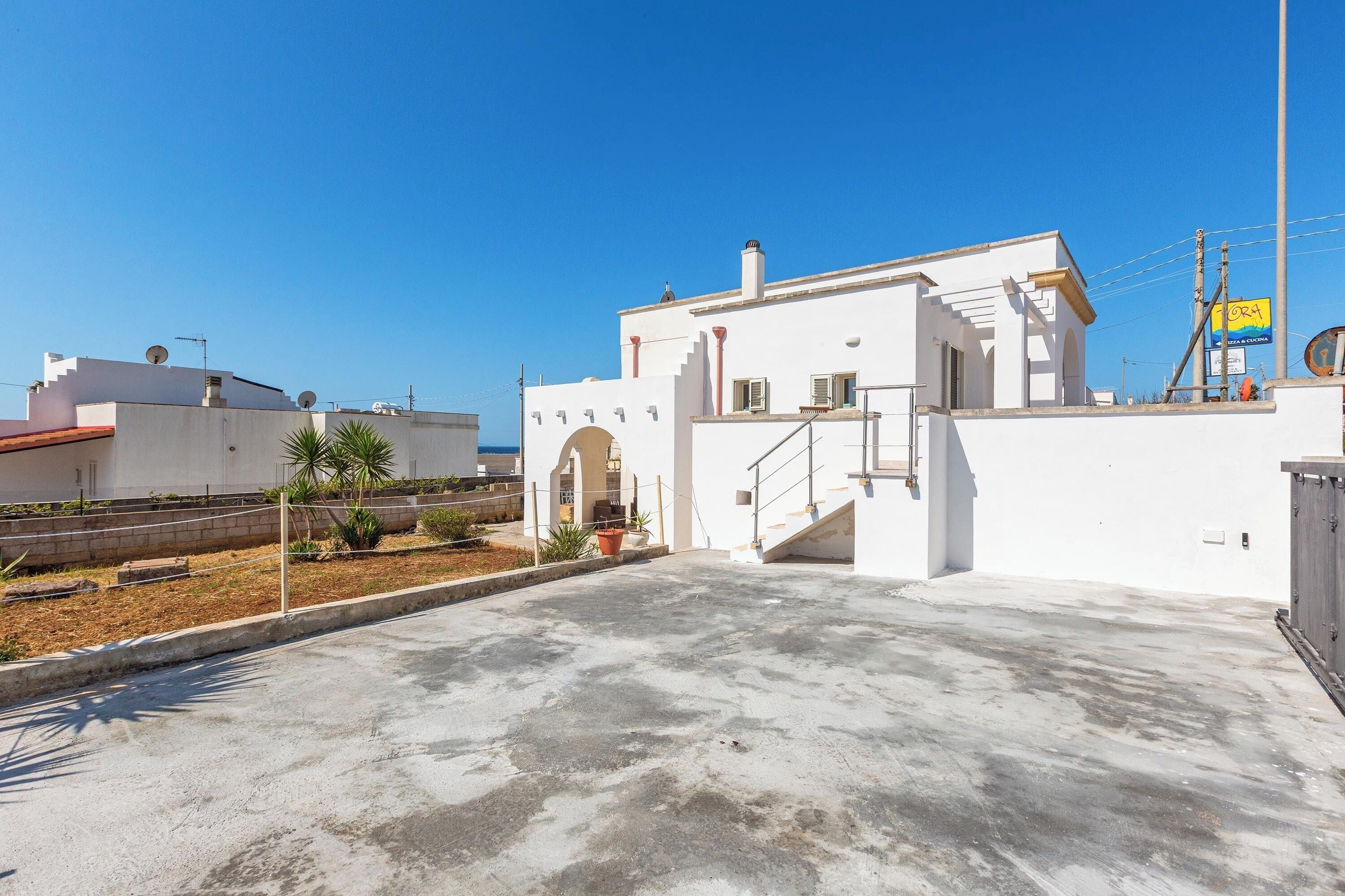 A white building with a flat roof, a small staircase, and a satellite dish.