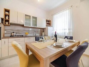 A modern kitchen with a dining table set for two, equipped with basic amenities. - Apartment Stella, Medulin (Marčana)