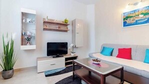 Een moderne woonkamer met een bank, tv en een schilderij aan de muur.