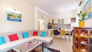 Een woonkamer met een bank, salontafel en een eethoek met stoelen en een tafel.