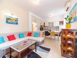 A living room with a sofa, coffee table, and a dining area with chairs and a table. - Apartment Stella, Medulin (Marčana)