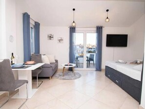 A modern living room with a sofa, dining table, and a TV mounted on the wall. - Apartment Sun, Pula (Marčana)