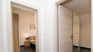 Un pasillo con una cama, una mesita de noche y una puerta.