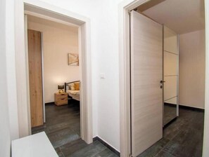 Ein Flur mit einem Bett, einem Nachttisch und einer Tür.