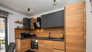 Una cocina moderna con armarios de madera, encimera negra y horno empotrado.
