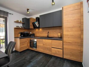 Eine moderne Küche mit Holzschränken, einer schwarzen Arbeitsplatte und einem eingebauten Backofen.