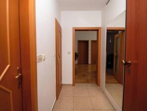 A hallway with wooden doors, a tiled floor, and a visible door at the end leading to another room. - Vallis Apartment, Pula (Marčana)