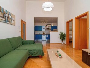 A modern living room with a green sofa, a coffee table with a plant, and a view into the kitchen area. - Vallis Apartment, Pula (Marčana)