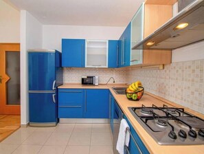 A kitchen with blue cabinets, a microwave, a gas stove, and a fruit bowl on the counter. - Vallis Apartment, Pula (Marčana)