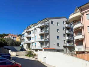 A multi-story residential building with balconies, a clear sky, and a street in the foreground. - Vallis Apartment, Pula (Marčana)