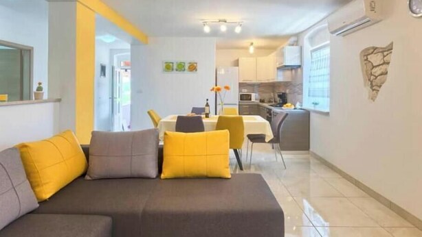A modern living room with a sofa, a dining area with a table and chairs, and a kitchen in the background. - Apartment Viola, Medulin (Marčana)