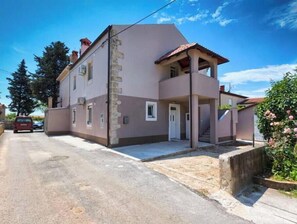 Ein zweigeschossiges Wohnhaus mit Balkon, Garage und Auffahrt.