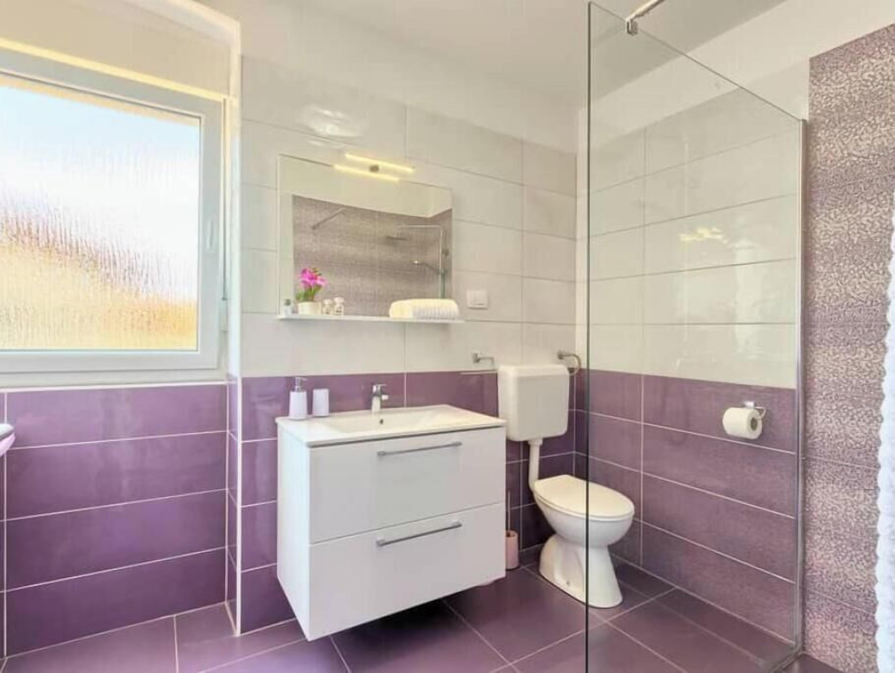 Un baño con lavamanos blanco, inodoro y cabina de ducha de vidrio.