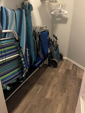 Een kamer met houten vloer, een bed met een gestreept dekbed en een rolstoel.