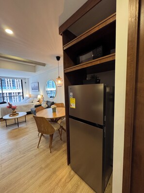 Eine moderne Küche mit einem Einbaukühlschrank, Holzregalen und einem Essbereich mit Tisch und Stühlen.