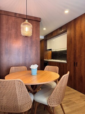 Ein Essbereich mit einem runden Holztisch, Korbstühlen und einer hängenden Lampe.