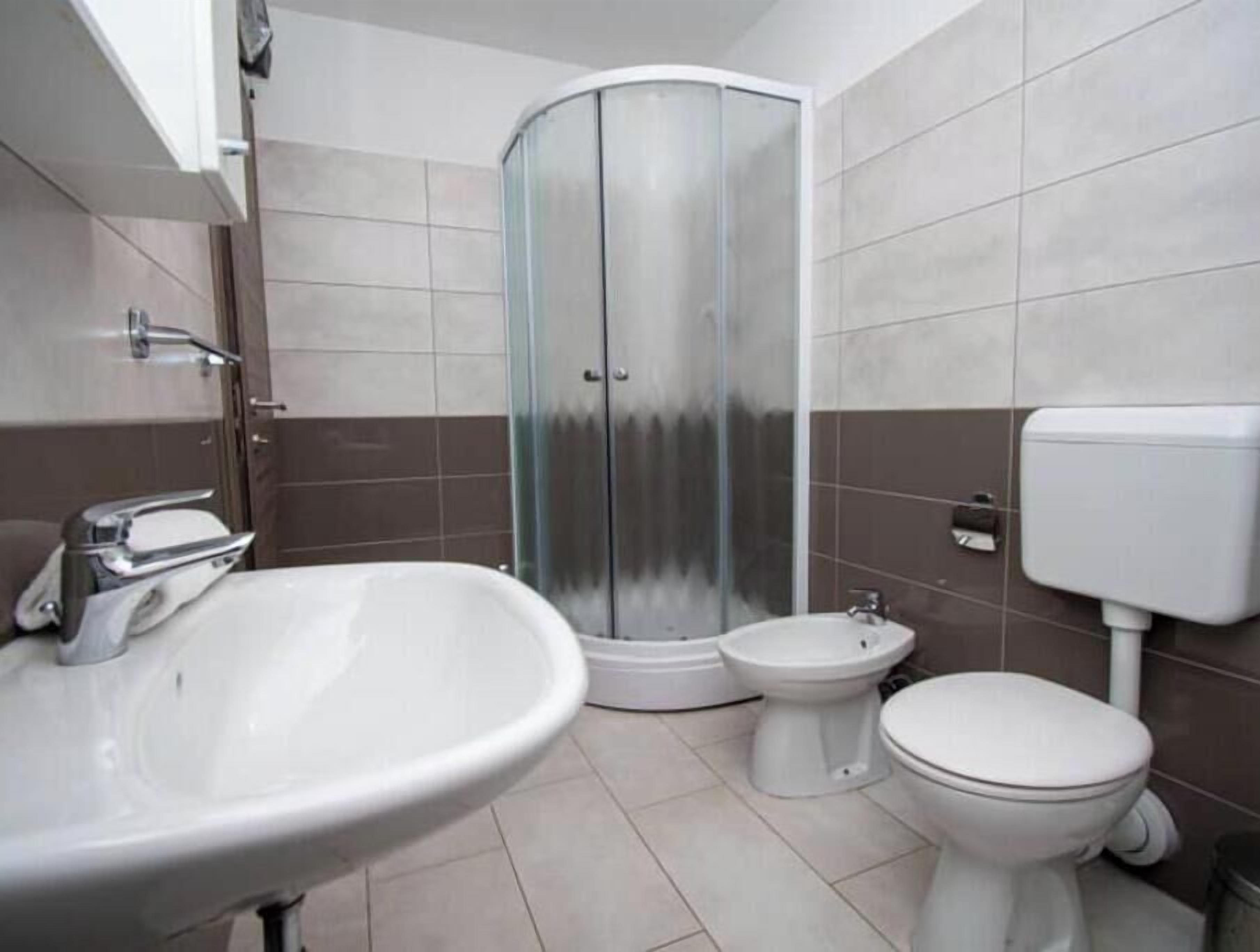 A bathroom with a sink, toilet, bidet, and a glass-enclosed shower.