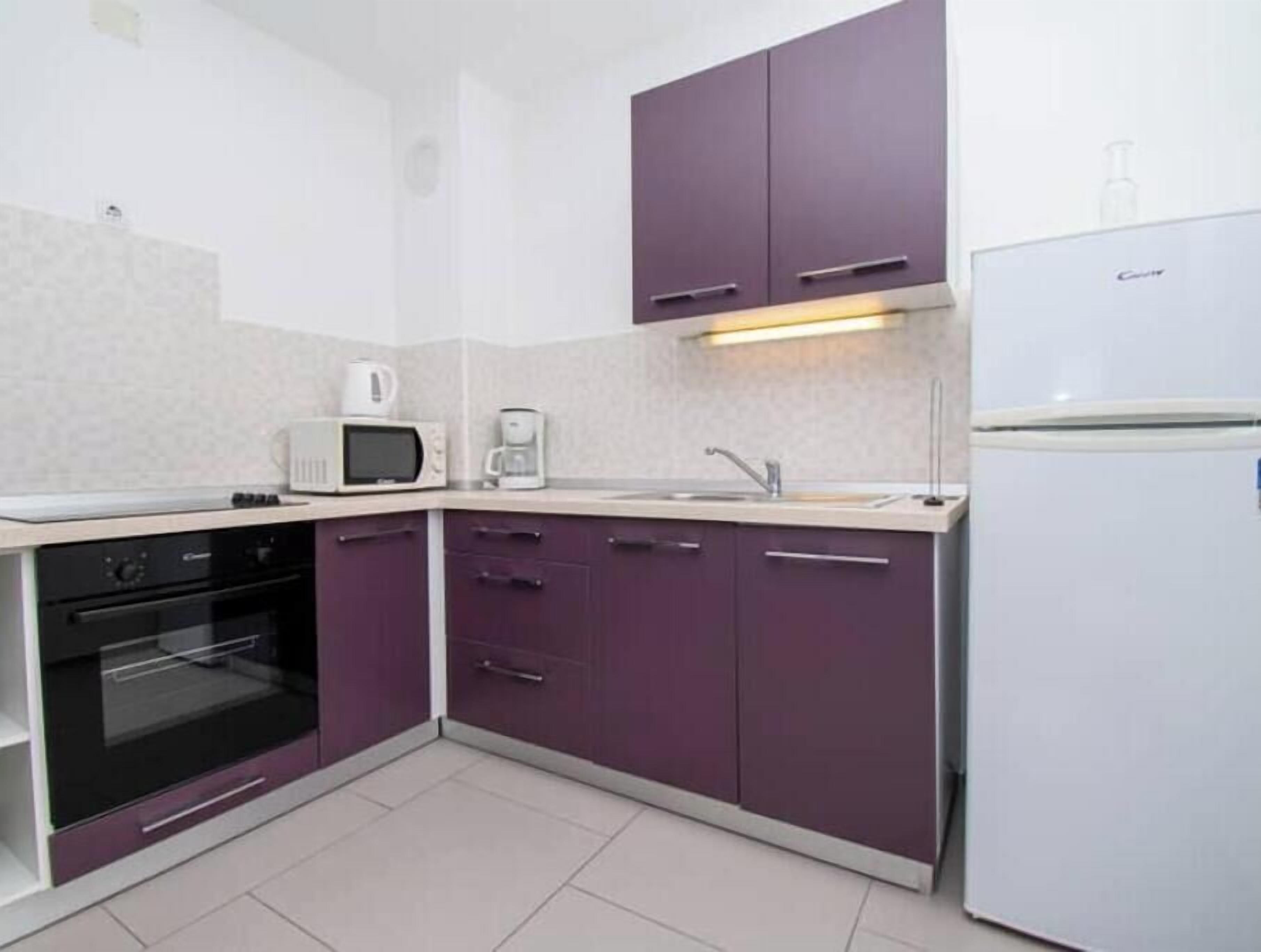 Una cocina compacta equipada con microondas, cafetera, horno, lavaplatos y refrigerador.