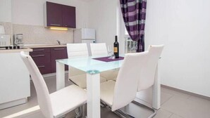 A compact kitchen with a dining area, including a glass table and white chairs. - A01 - C: Lotus Apartment (Marčana)