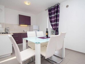 A compact kitchen with a dining area, including a glass table and white chairs. - A01 - C: Lotus Apartment (Marčana)