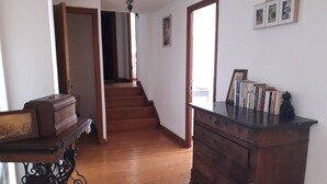 Un pasillo con suelo de madera, una escalera, un aparador de madera y una mesa con un marco de fotos.