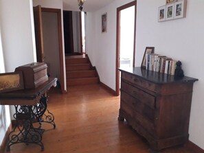 Ein Flur mit Holzboden, einer Treppe, einer Holzkommode und einem Tisch mit einem Bilderrahmen.