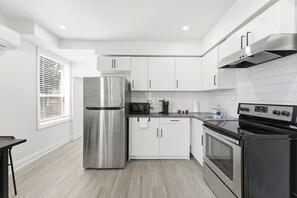 A modern kitchen with stainless steel appliances, white cabinetry, and a black countertop. - Bright Renovated 1BR Suite · Monthly Stays · 5 Min to Downtown & Hospital (Brantford)