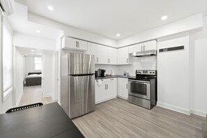 Une cuisine moderne avec des meubles blancs, des appareils en acier inoxydable et un plancher en bois.