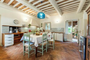 A kitchen with a dining table, chairs, a clock, and a hanging light fixture. - Pool Villa with SPA in Perugia city (Perugia)