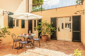 A patio with a table and chairs, a potted plant, and a door with shutters. - Pool Villa with SPA in Perugia city (Perugia)
