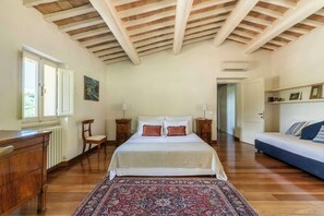 A bedroom with a large bed, a wooden dresser, a chair, a nightstand, a radiator, a window, and a door leading to another room. - Pool Villa with SPA in Perugia city (Perugia)