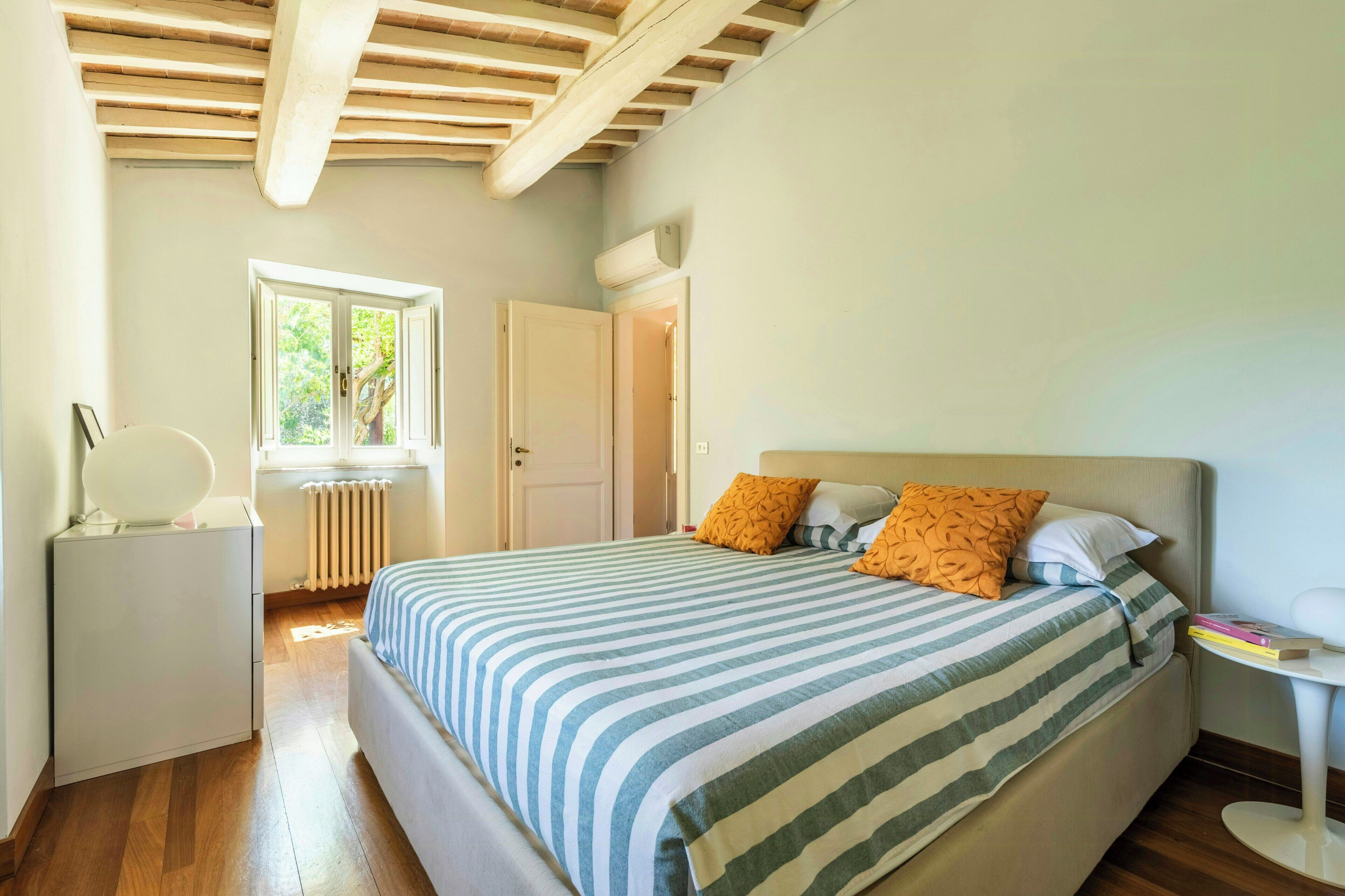 Une chambre à coucher avec un lit, un radiateur, une fenêtre et une table de chevet.