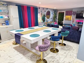 A modern dining area with a white table, bar stools, and a sofa.
