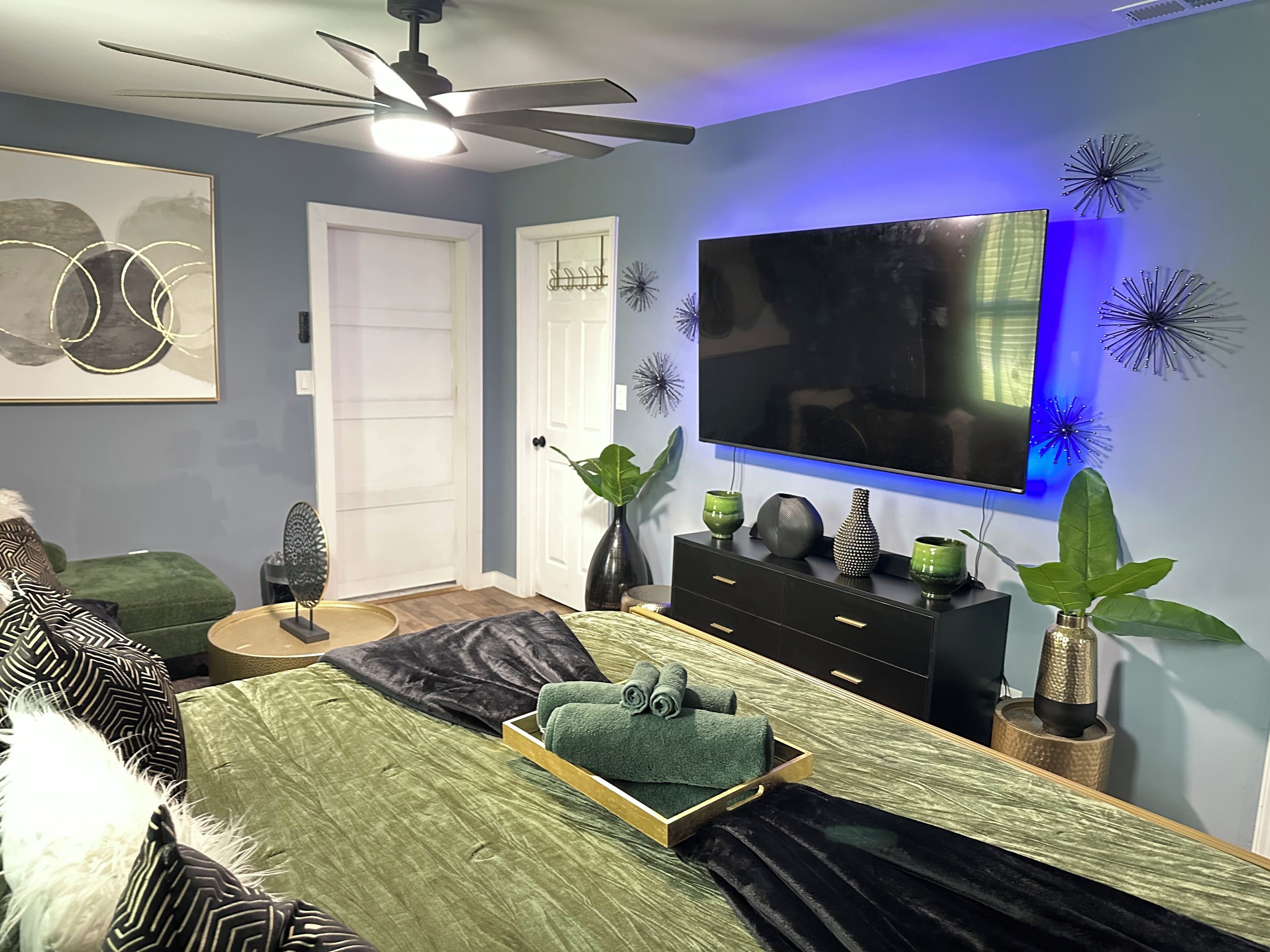 A bedroom with a bed, a dresser, a television, and decorative wall art.