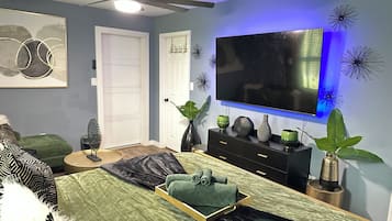 A bedroom with a bed, a dresser, a television, and decorative wall art.