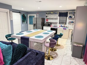 Una cocina moderna con comedor, que incluye una encimera de mármol, horno empotrado y refrigerador.