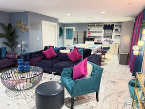 A modern living room with a sofa, ottoman, and a dining area with a table and chairs.