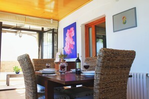 A dining area with a table set for two, wicker chairs, a bottle of wine, and a potted plant. - CAN SERENA. CAN PICAFORT. MALLORCA. NEAR THE BEACH (Can Picafort)