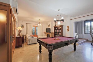 Une pièce équipée d’une table de billard, d’un canapé, d’une bibliothèque et d’un téléviseur.