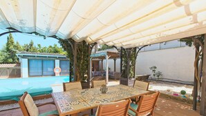 An outdoor patio with a table and chairs, a pool, and a covered area with plants. - CAN SERENA. CAN PICAFORT. MALLORCA. NEAR THE BEACH (Can Picafort)