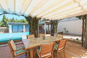 An outdoor patio with a table and chairs, a pool, and a covered area with plants. - CAN SERENA. CAN PICAFORT. MALLORCA. NEAR THE BEACH (Can Picafort)