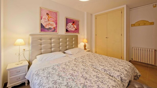 A bedroom with a bed, two bedside lamps, a headboard, a door, and two framed pictures on the wall. - CAN SERENA. CAN PICAFORT. MALLORCA. NEAR THE BEACH (Can Picafort)