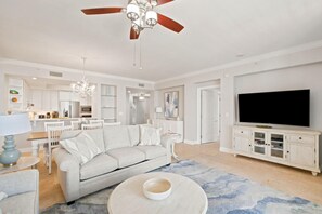 A modern living room with a sofa, TV, and dining area. - Indigo East 402 (Pensacola)