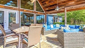 Un patio al aire libre con mobiliario de mimbre, piso de piedra y techo de madera.