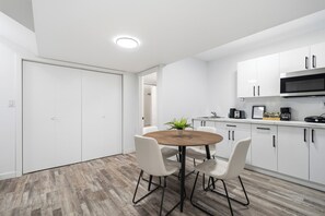 Eine moderne Küche mit weißen Schränken, einem Holztisch und einem Blumentopf.