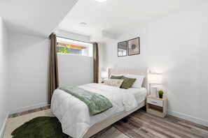 Een moderne slaapkamer met een bed, nachtkastje en een raam met gordijnen.